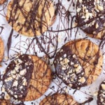 Peanut butter cookies on a sheet of parchment drizzled with chocolate.