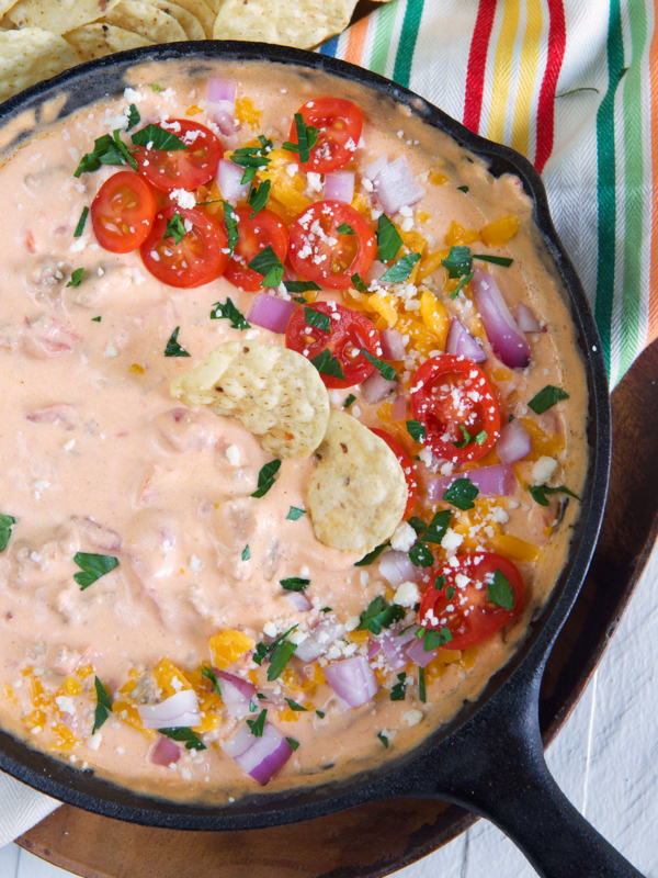 Two round chips have been placed in the skillet filled with dip.