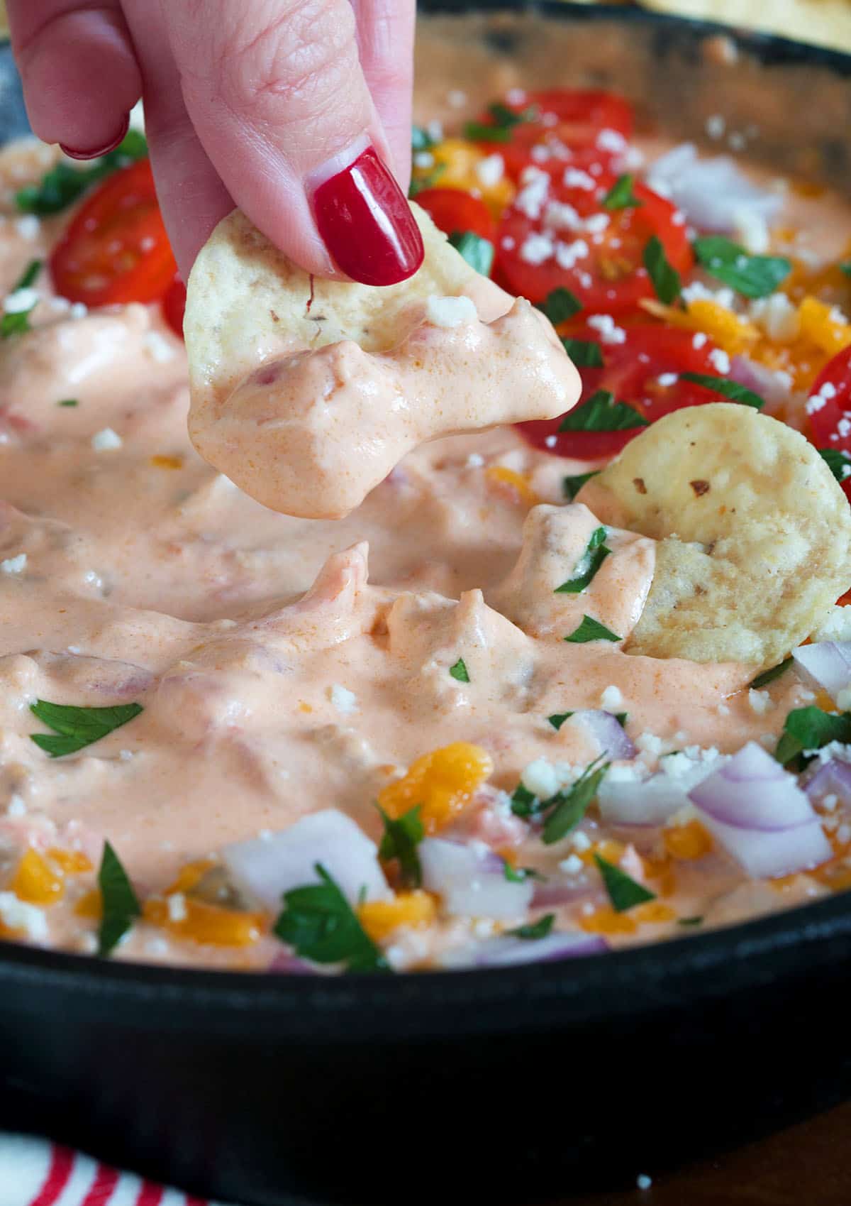 A single chip is being lifted from the cheesy dip.