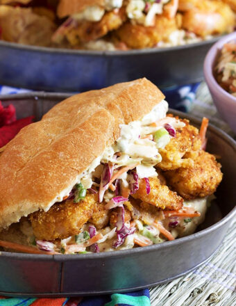 Fried Shrimp Po boy with slaw and sauce plated in a steel tray.