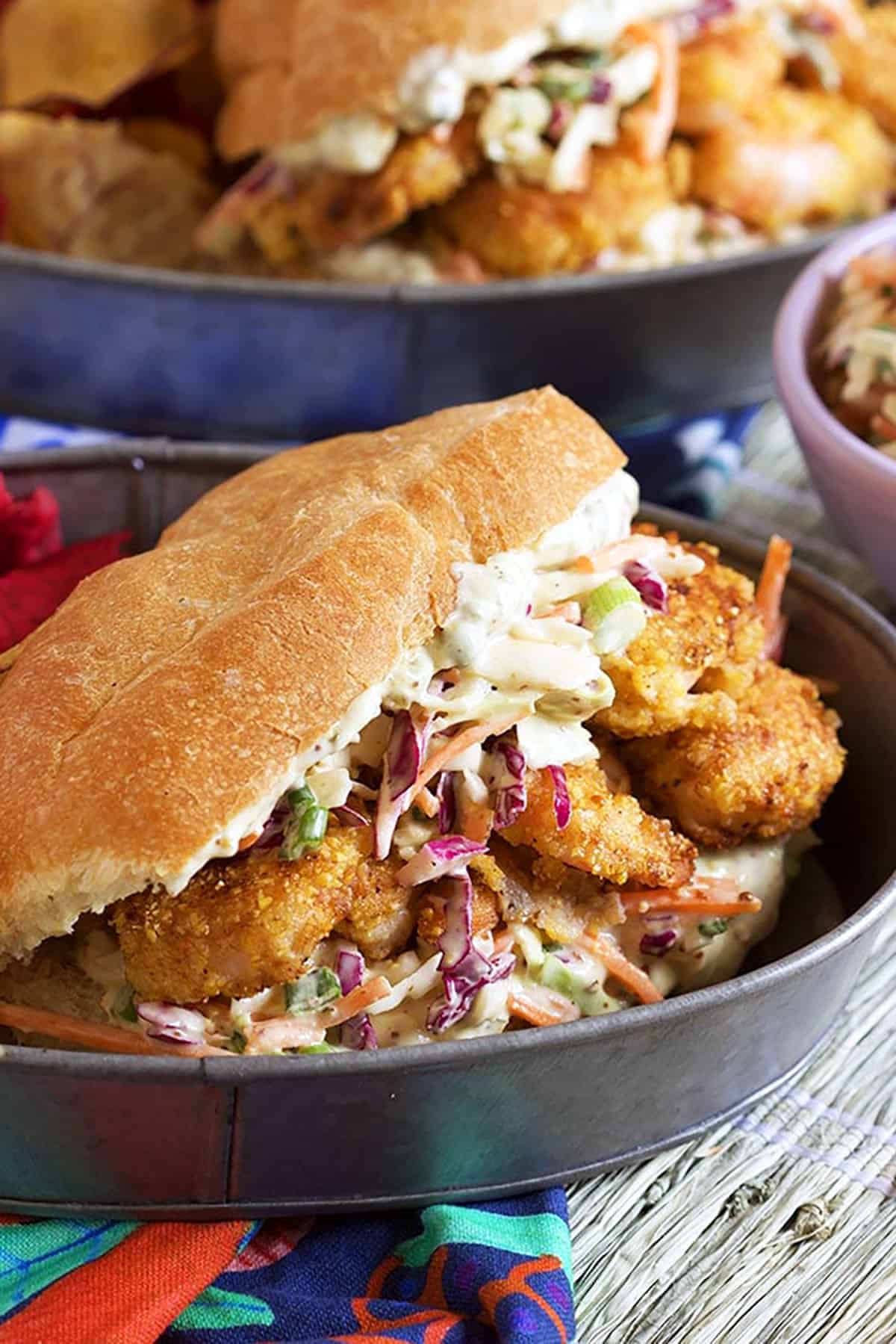 Fried Shrimp Po boy with slaw and sauce plated in a steel tray.