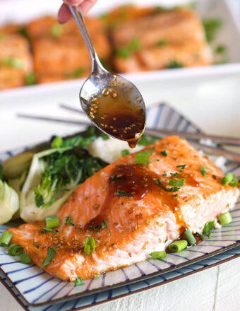 Baked Teriyaki Salmon with teriyaki sauce being drizzled on top with a spoon.