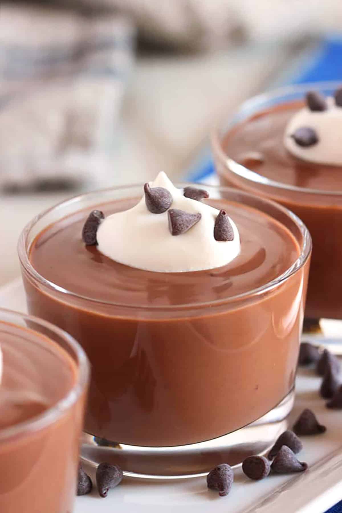 Chocolate pudding in a glass dish with a bit of whipped cream on top.