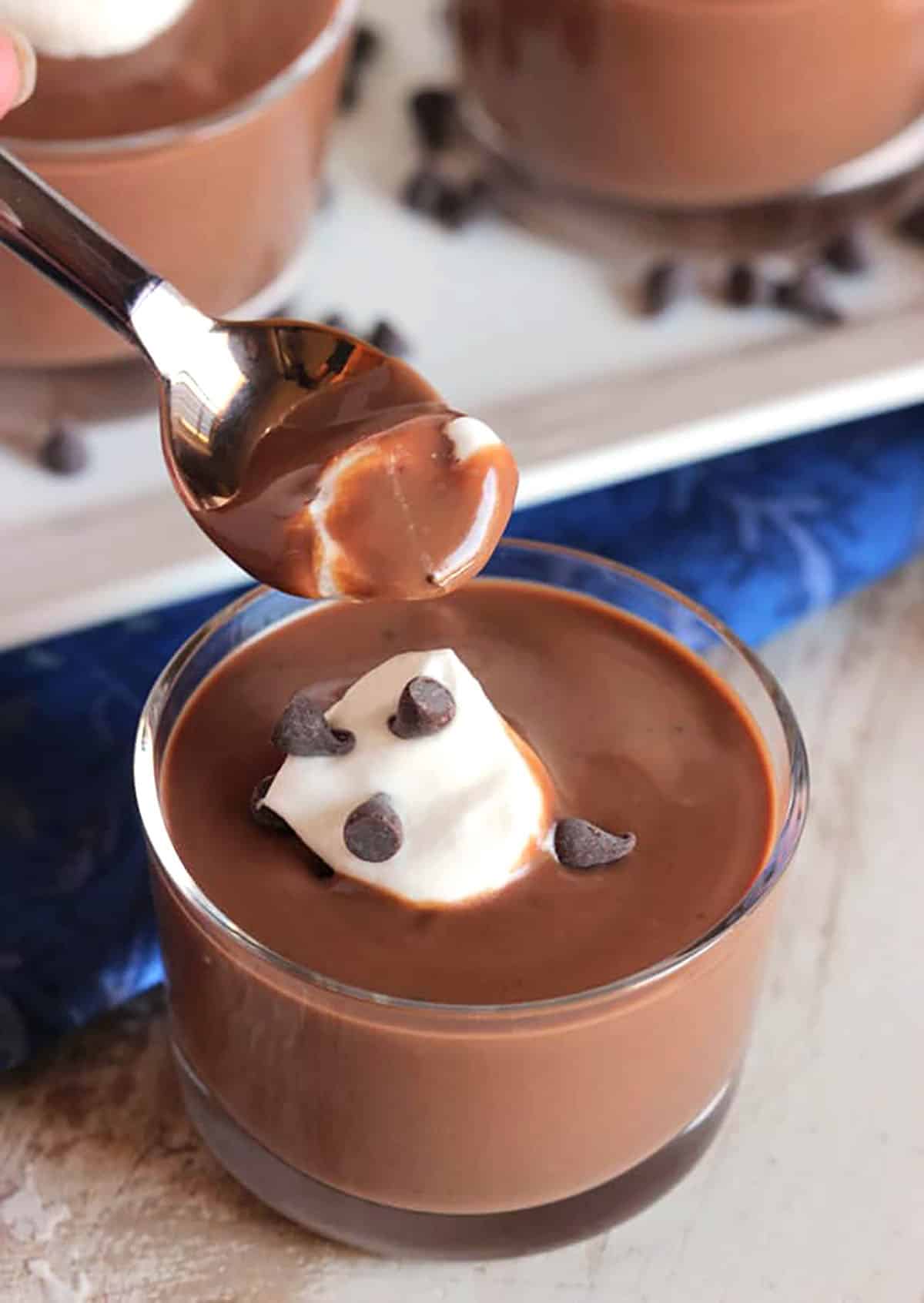 Chocolate pudding in a glass dish with a spoonful of pudding over top of it.