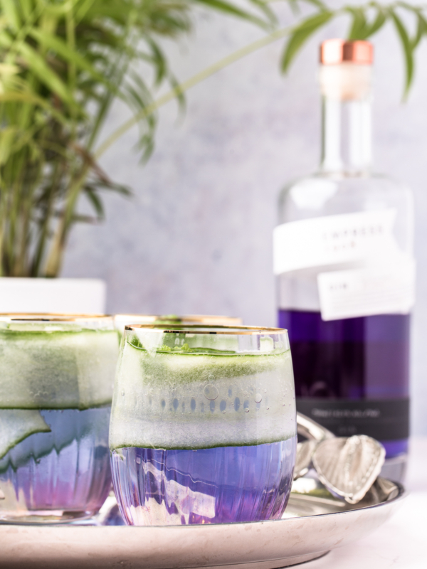 Multiple gin cocktails are presented on a serving platter next to a bottle of Empress Gin.