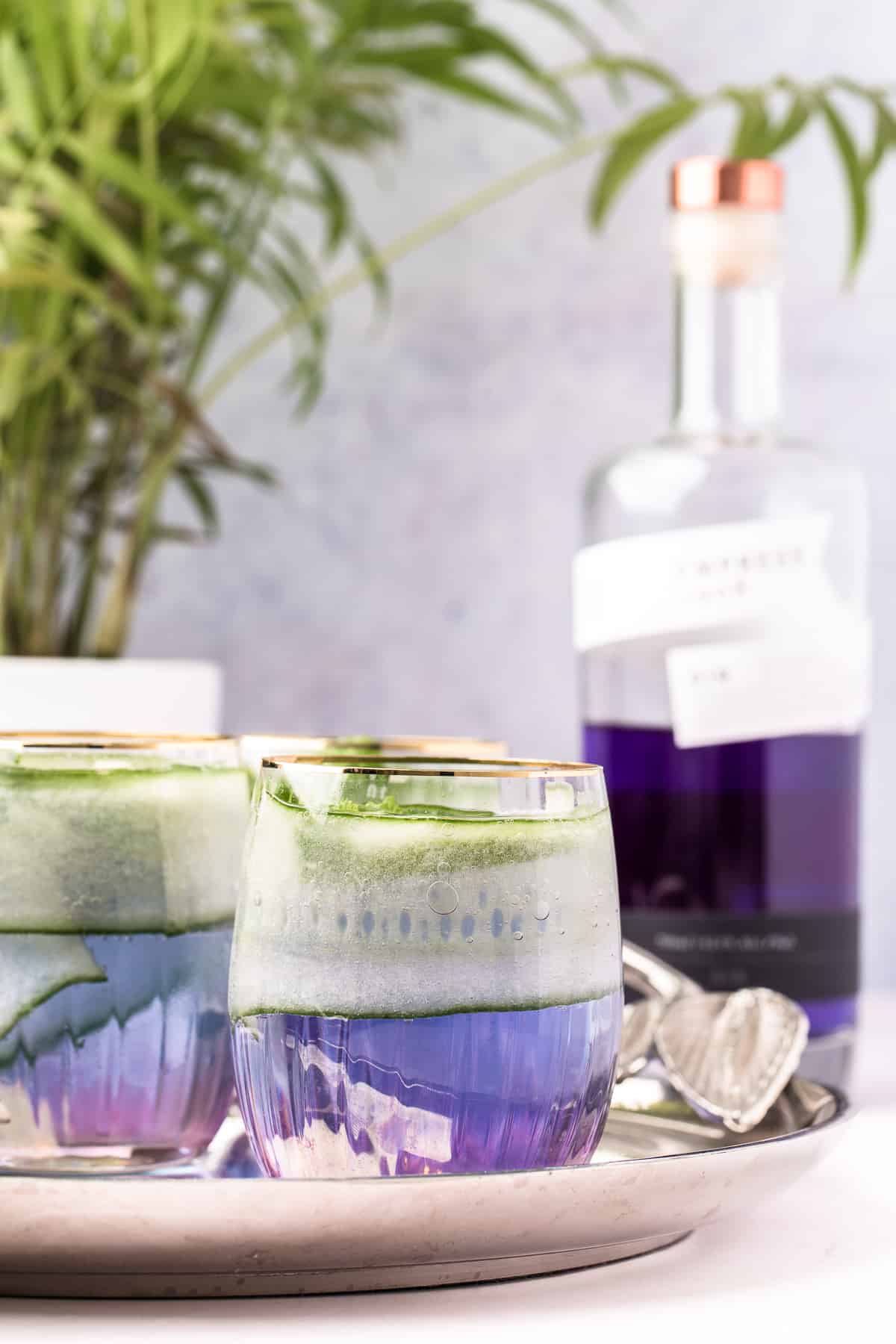 Multiple gin cocktails are presented on a serving platter next to a bottle of Empress Gin.