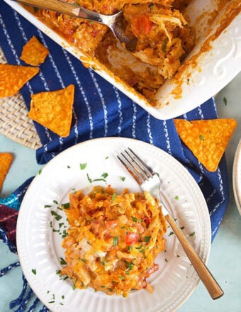 Dorito Chicken Casserole in a white baking dish with a blue napkin and a white plate and fork.