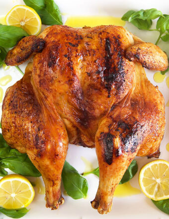 Overhead shot of spatchcock chicken on a white platter with lemons.