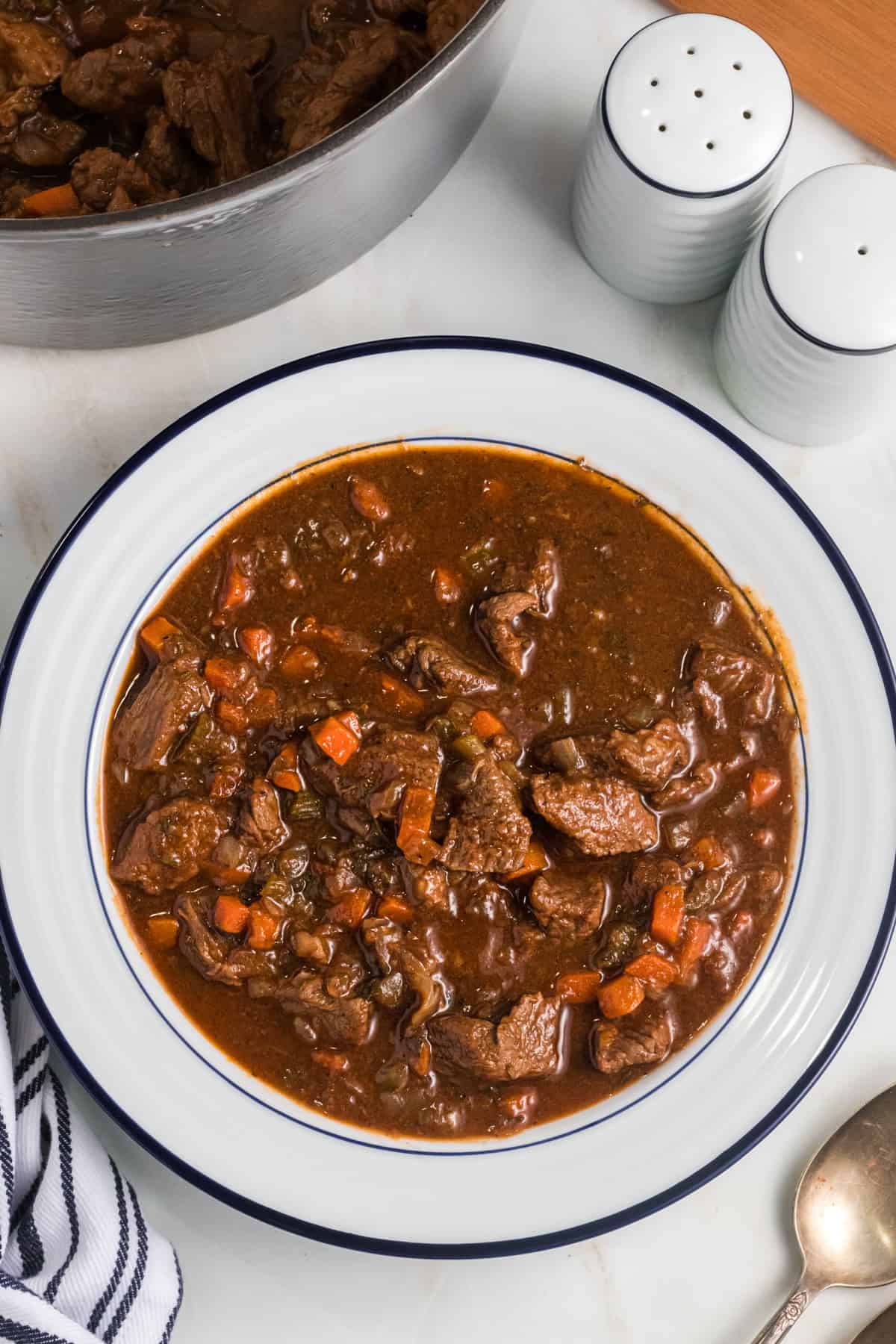 A white bowl is filled with beef stew.