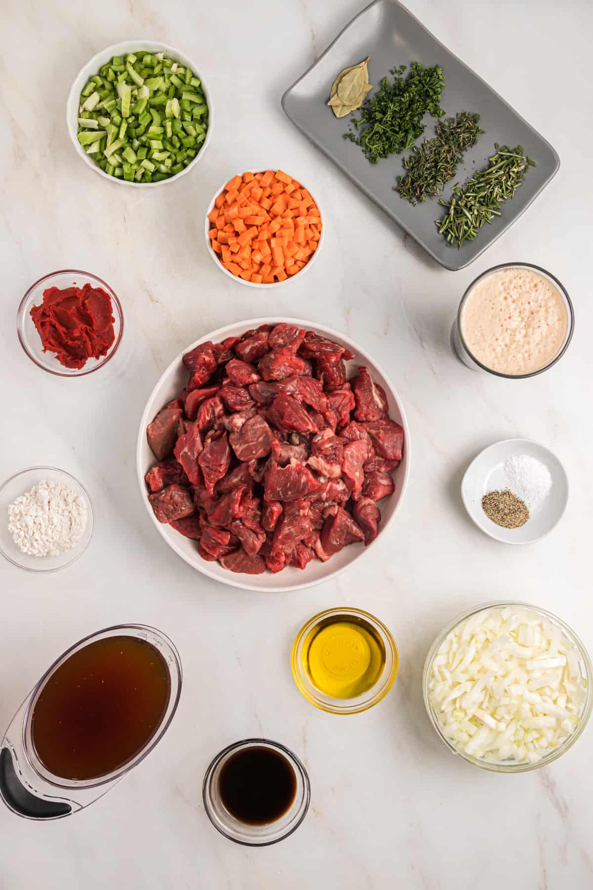 The ingredients for guinness beef stew are placed on a white surface.