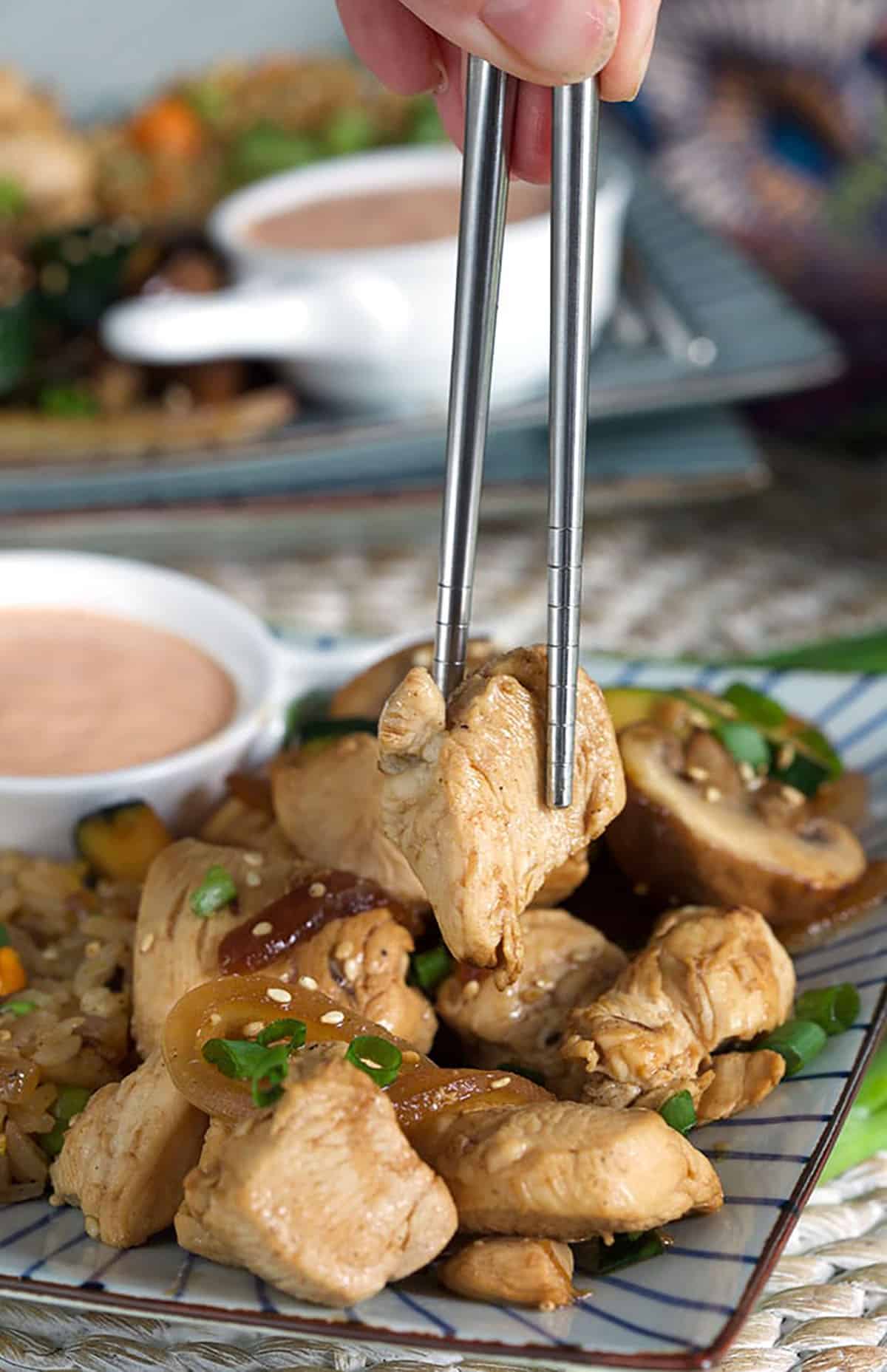 Hibachi chicken being picked up with silver chopsticks