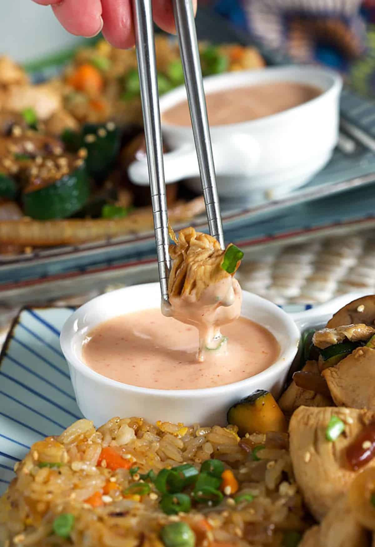 A piece of chicken is dipped into yum yum sauce.