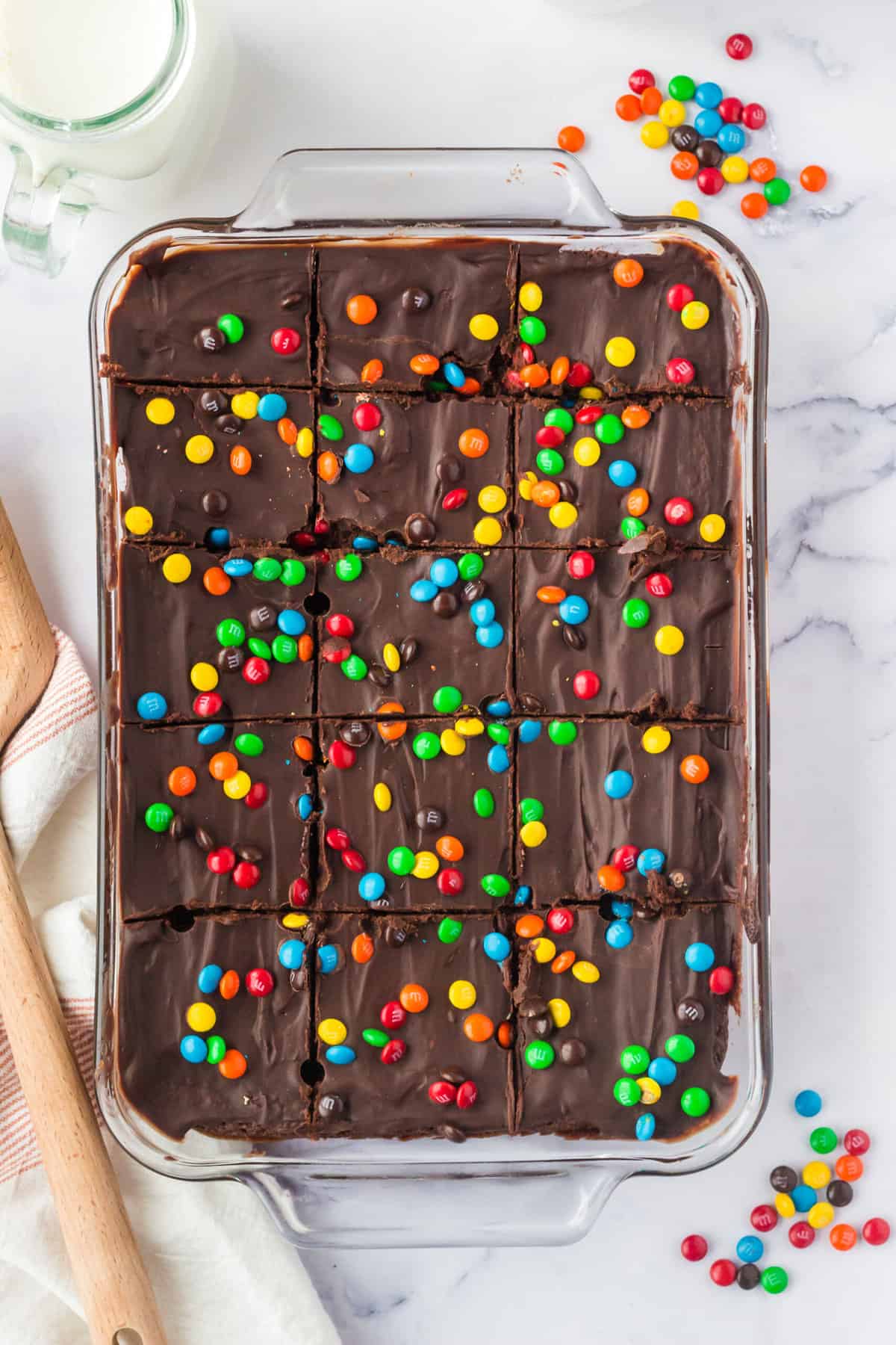 A baking dish is filled with frosted cosmic brownies, topped with M&M candies.