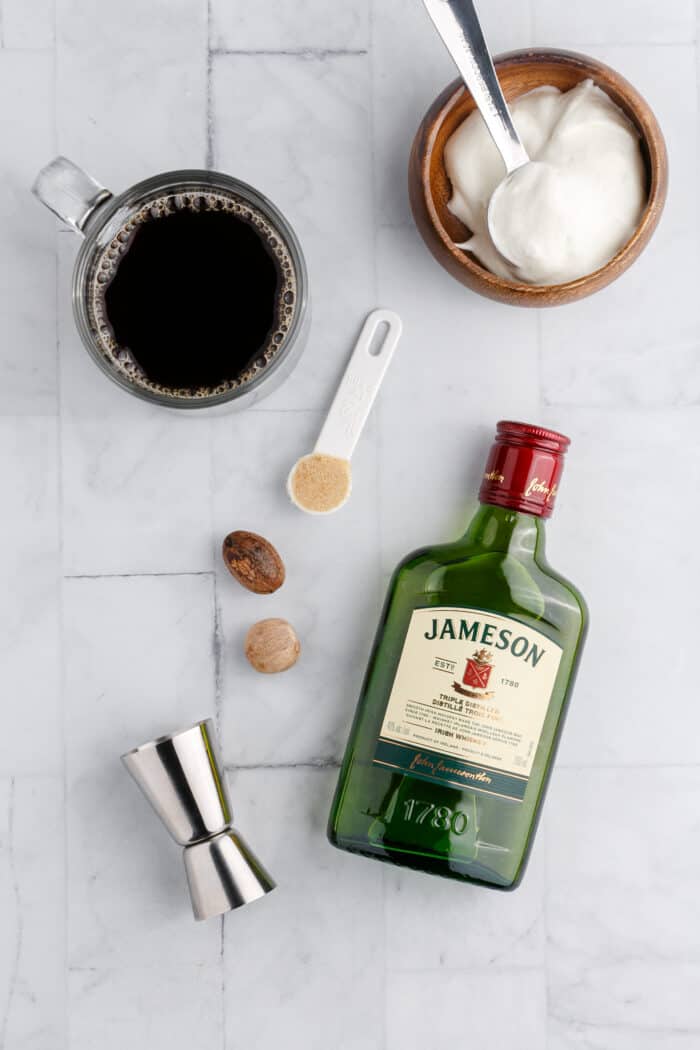 The ingredients for Irish coffee are spread out across a white surface.