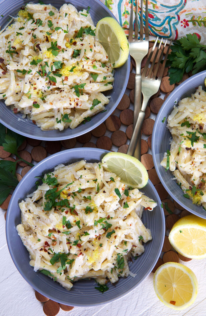 Three bowls of lemon ricotta pasta are placed on a tabletop.