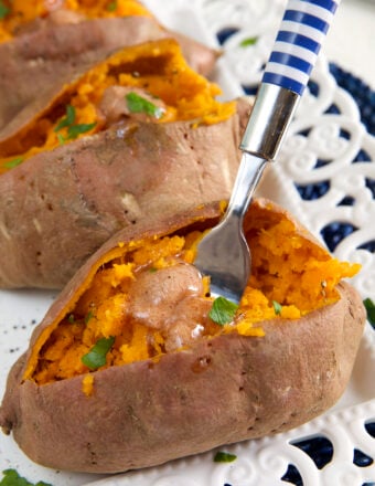 A blue and white striped fork is digging into a cooked sweet potato.