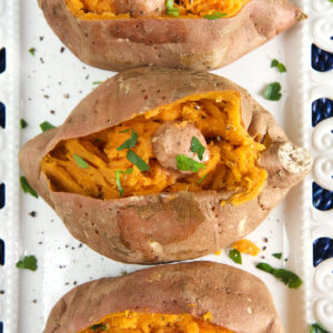 Three cooked, butter sweet potatoes are all split down the middle.