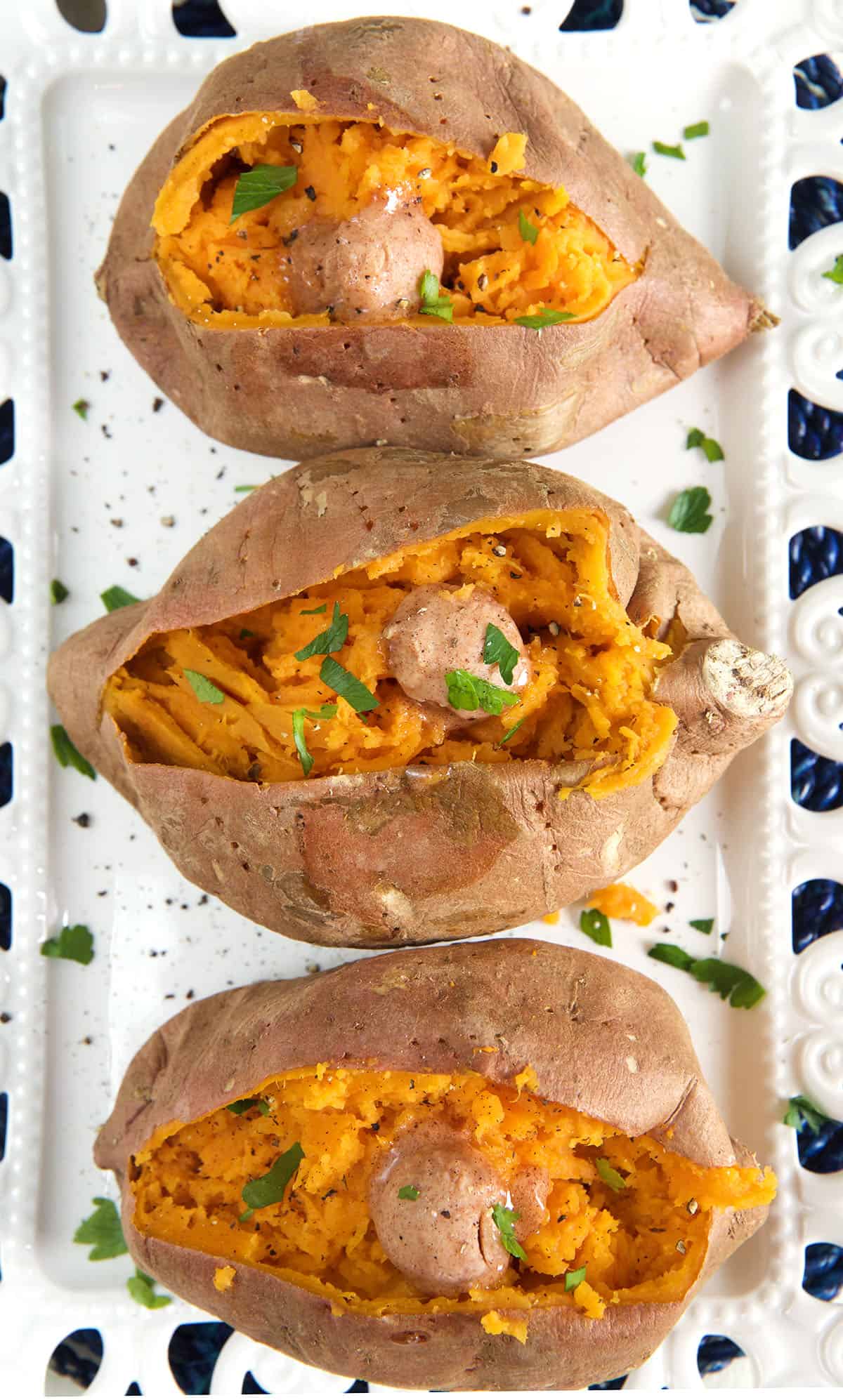 Three cooked, butter sweet potatoes are all split down the middle.
