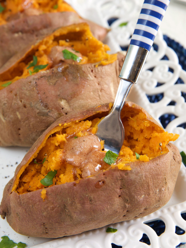 A blue and white striped fork is digging into a cooked sweet potato.