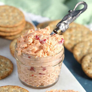 Pimento Cheese in a glass jar with a silver elephant spreader on a marble board