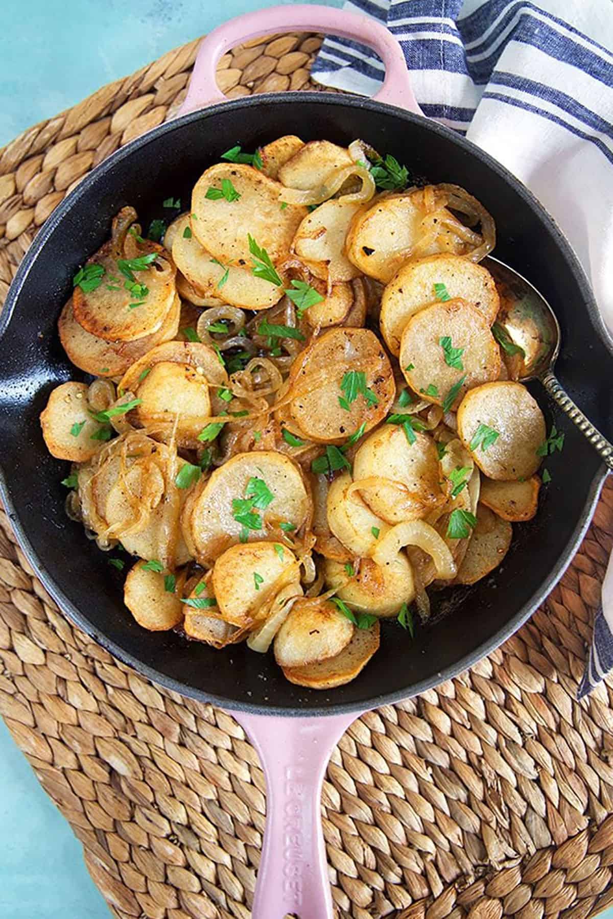 lyonnaise potatoes in a pink cast iron skillet.