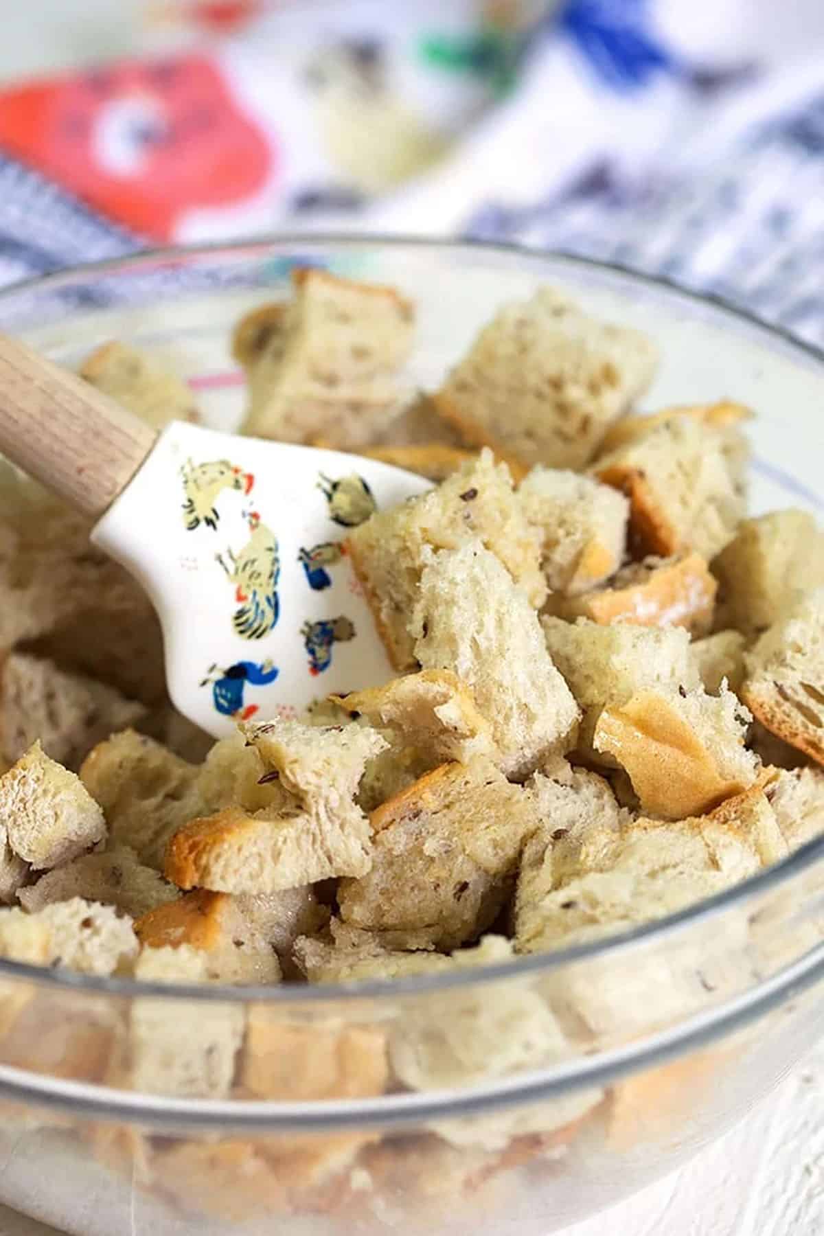 rye bread being tossed in a bowl with butter.