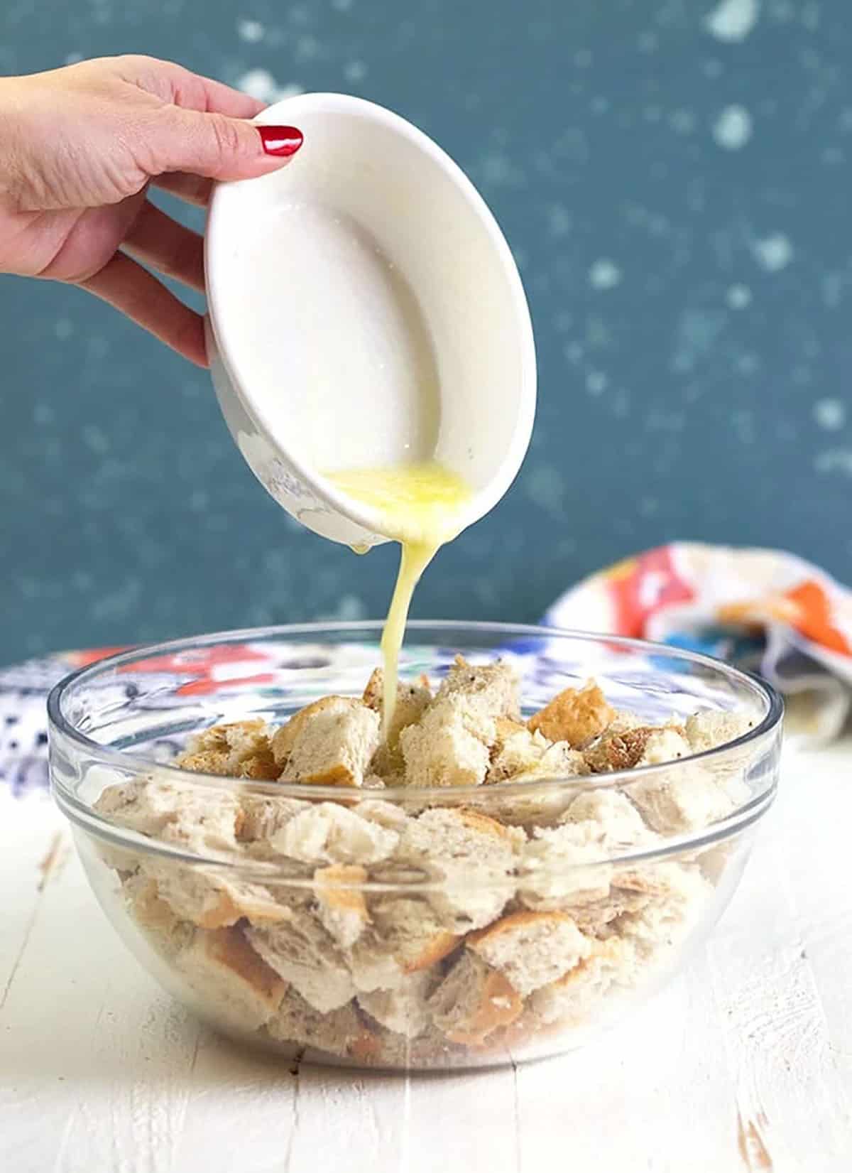 bowl of rye bread with buttering being poured over it.