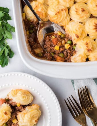 Overhead shot of shepherd's pie in a white casserole dish with a serving spoon.