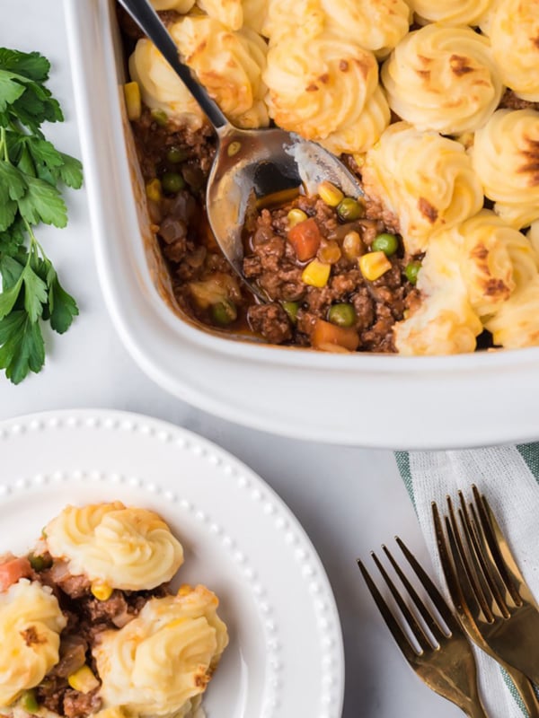 Overhead shot of shepherd's pie in a white casserole dish with a serving spoon.