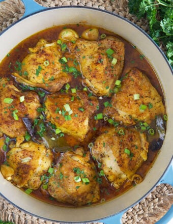 A dutch oven is filled with cooked chicken thighs.