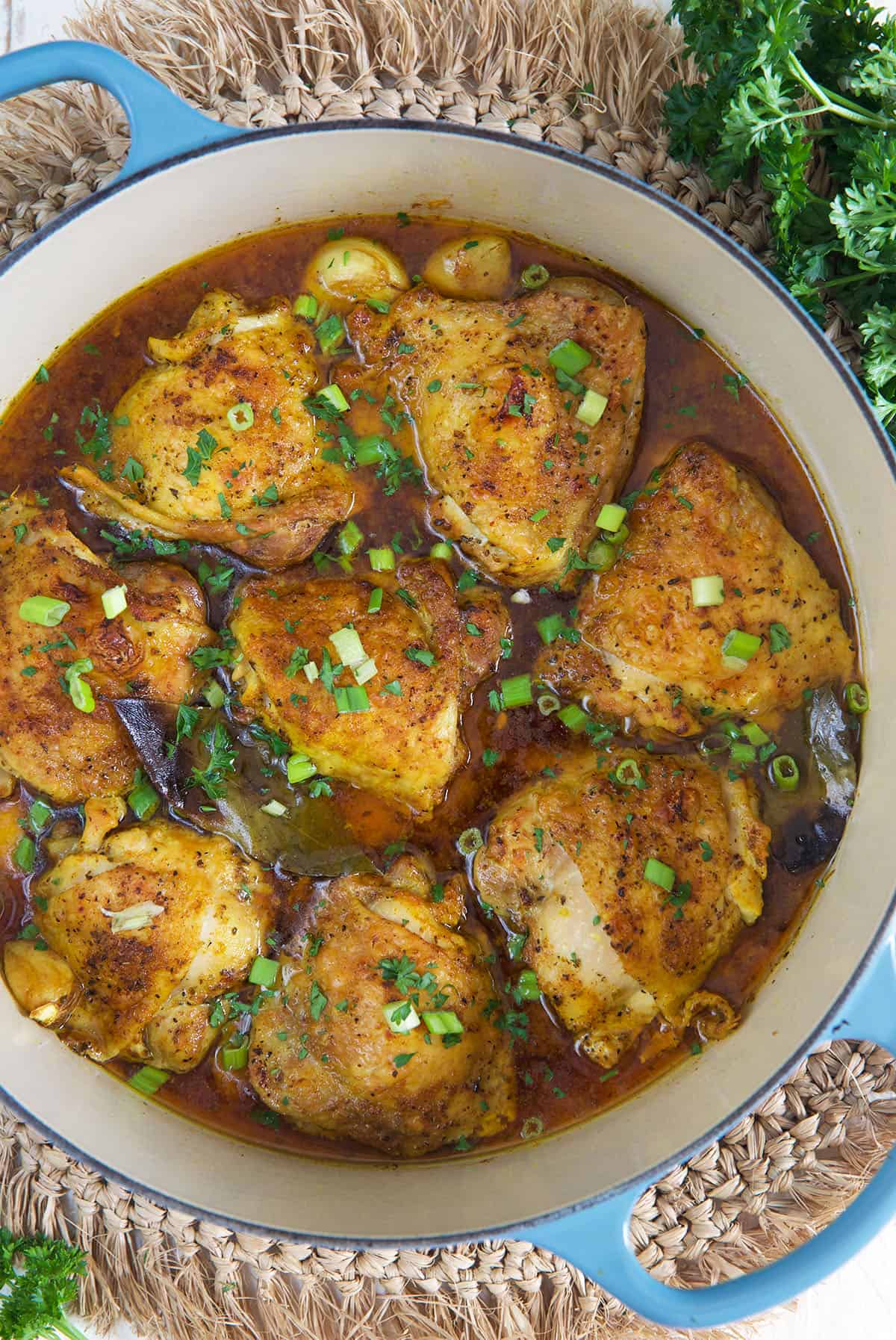 A dutch oven is filled with cooked chicken thighs.