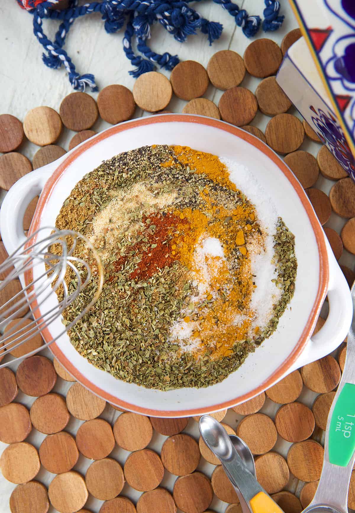 A white bowl is full of spices that are in the process of being whisked together.