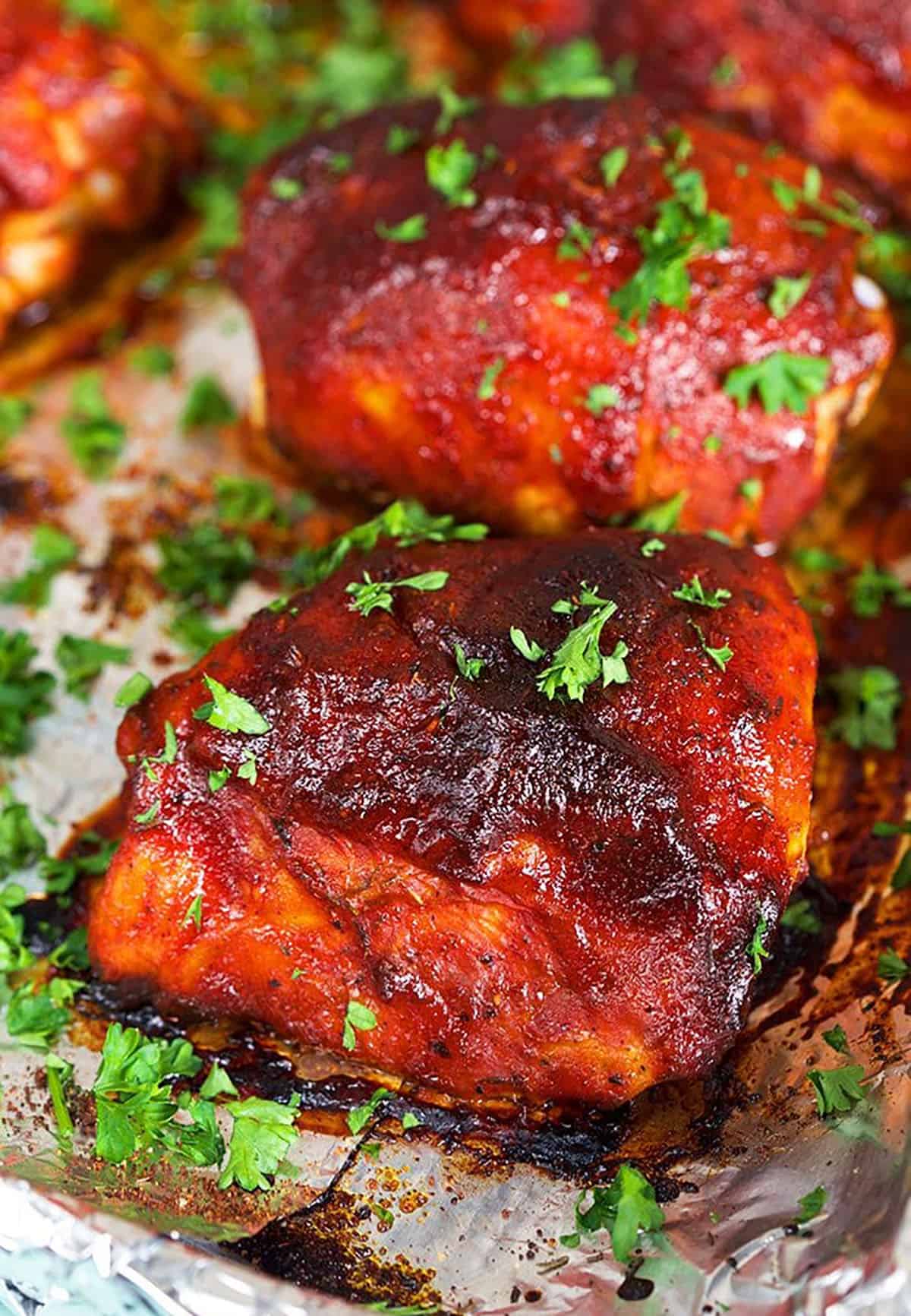 Close up of bbq chicken on a baking sheet with foil.