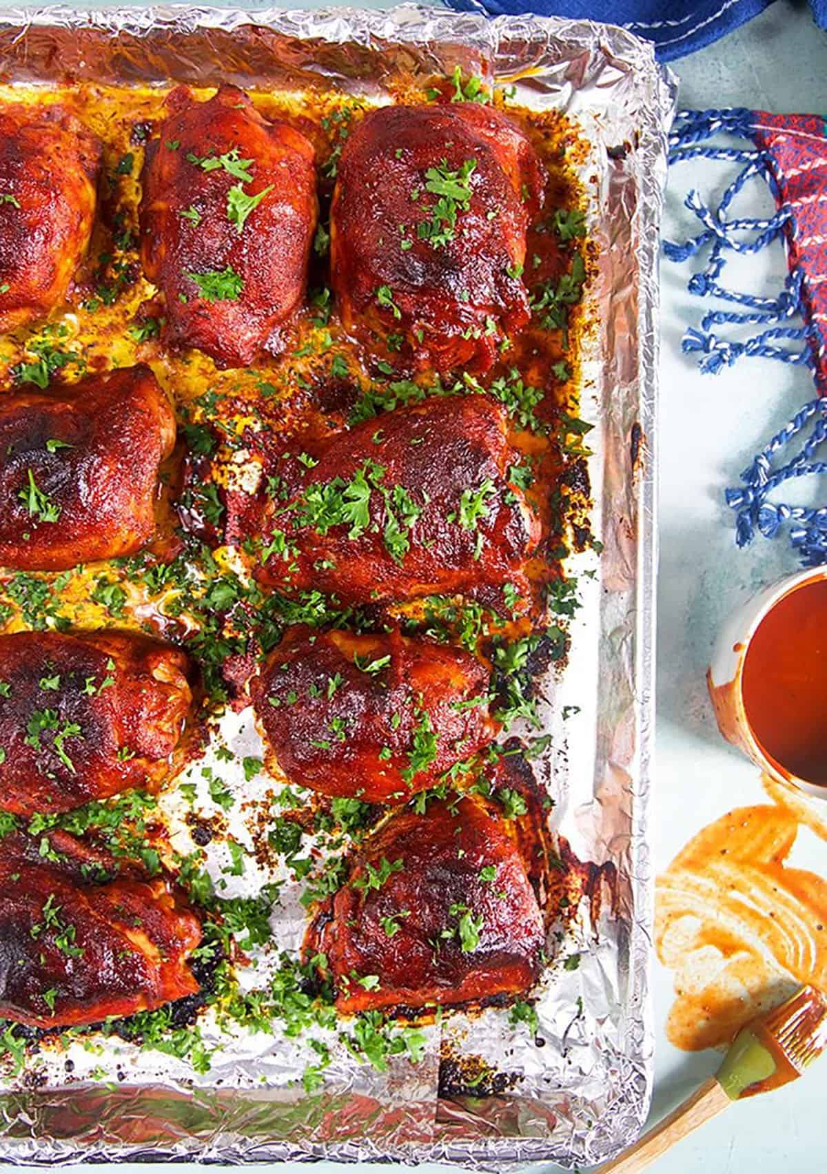 Overhead shot of bbq chicken on a baking sheet lined with aluminum foil.