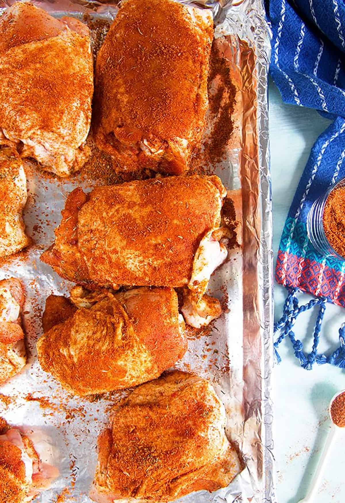 BBQ Chicken rubbed thighs on a baking sheet.