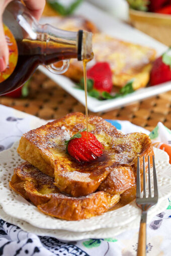 French Toast on a white plate with syrup being drizzled on top