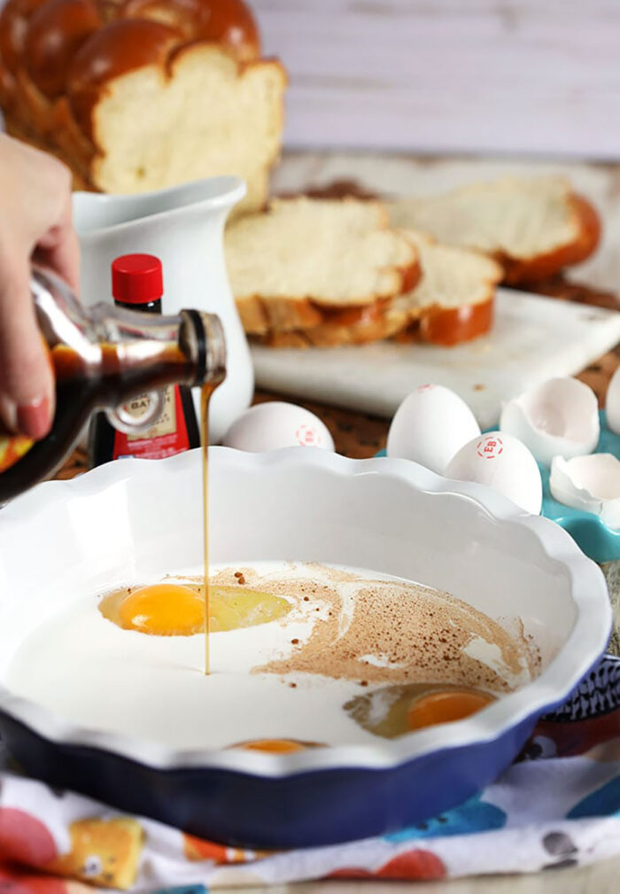 Ingredients for French toast in a pie plate with vanilla extract being added.