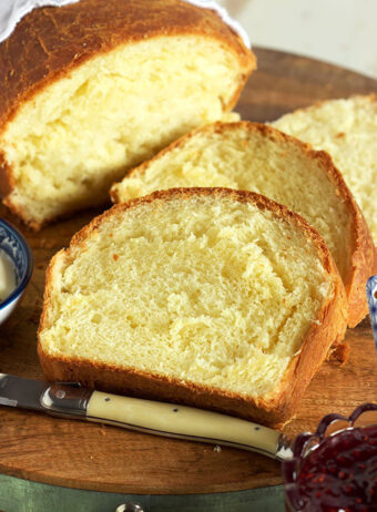 slices of brioche bread stacked on a cutting board with a knife.