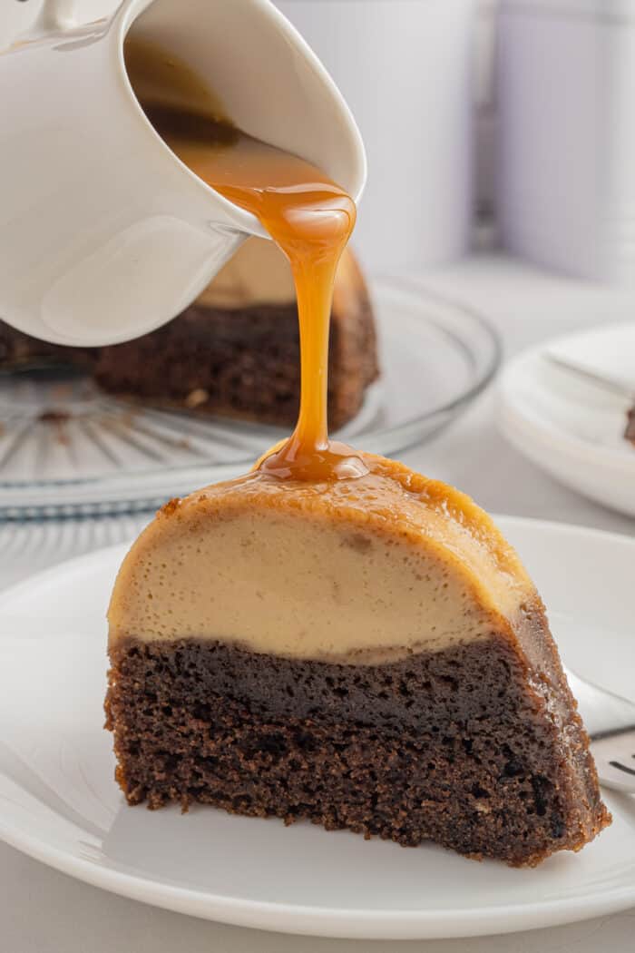 Caramel sauce is being poured on top of a slice of cake.