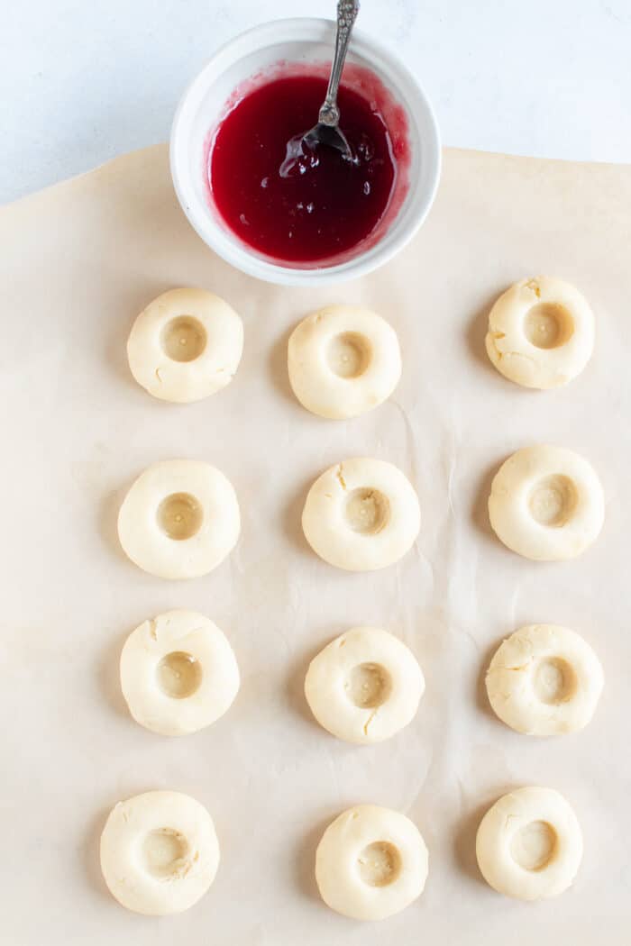 Cookies have been pressed into next to a white bowl of jam.