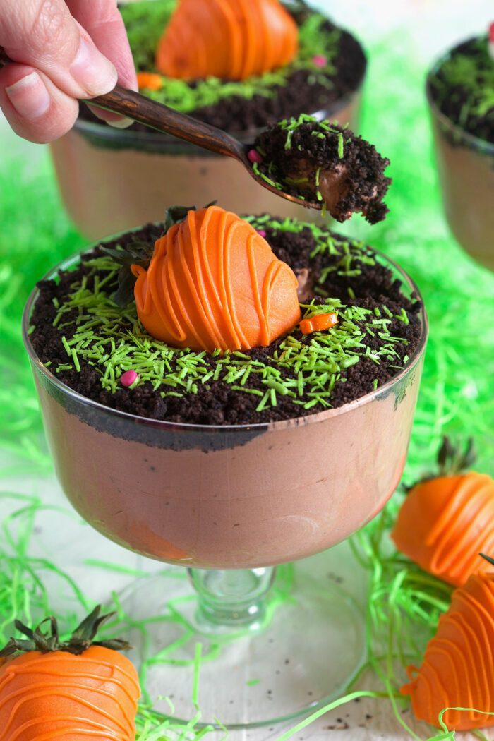 A spoonful of chocolate pudding is being lifted from the Easter dirt cup.
