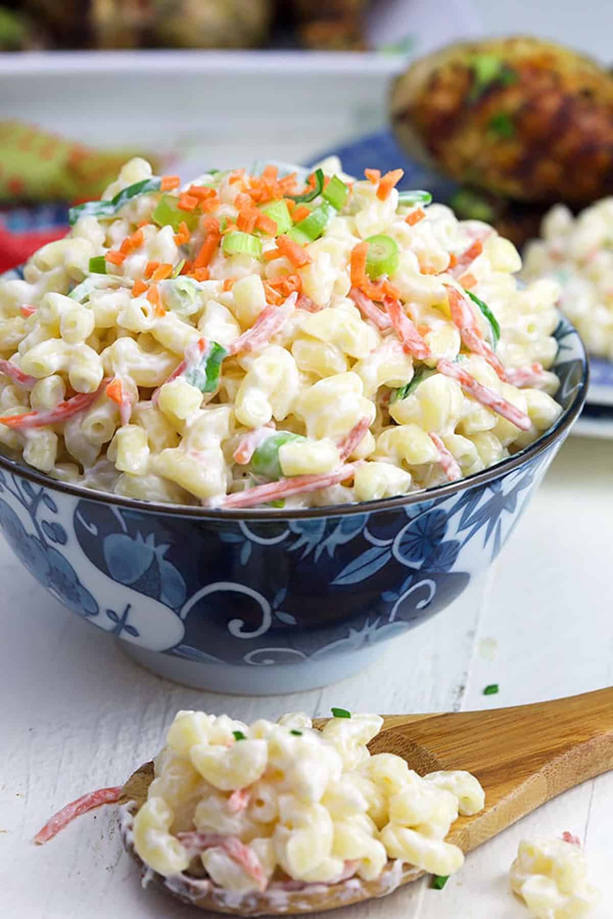Hawaiian Macaroni Salad in a blue and white bowl with a wooden spoon.