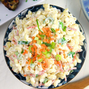 Overhead shot of macaroni salad in a blue bowl with a wooden spoon.