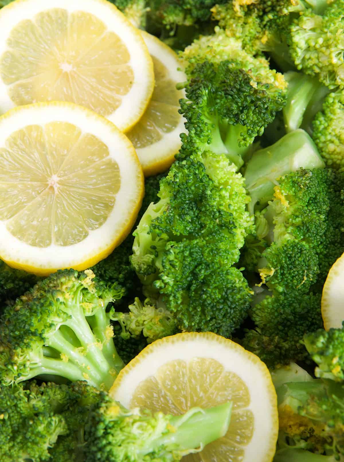 Lemon slices are placed on top of steamed broccoli.