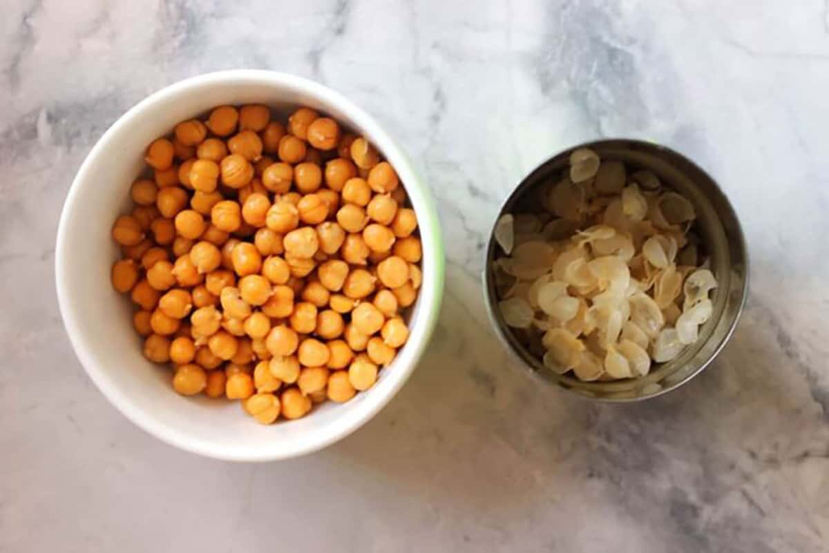 Bowl of chickpeas with the skins in a can next to it.
