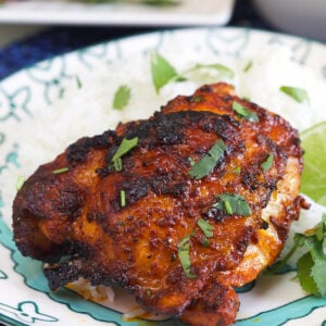 A cooked chicken thigh is garnished with fresh cilantro.