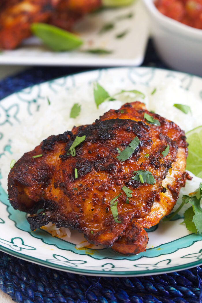 A cooked chicken thigh is garnished with fresh cilantro.