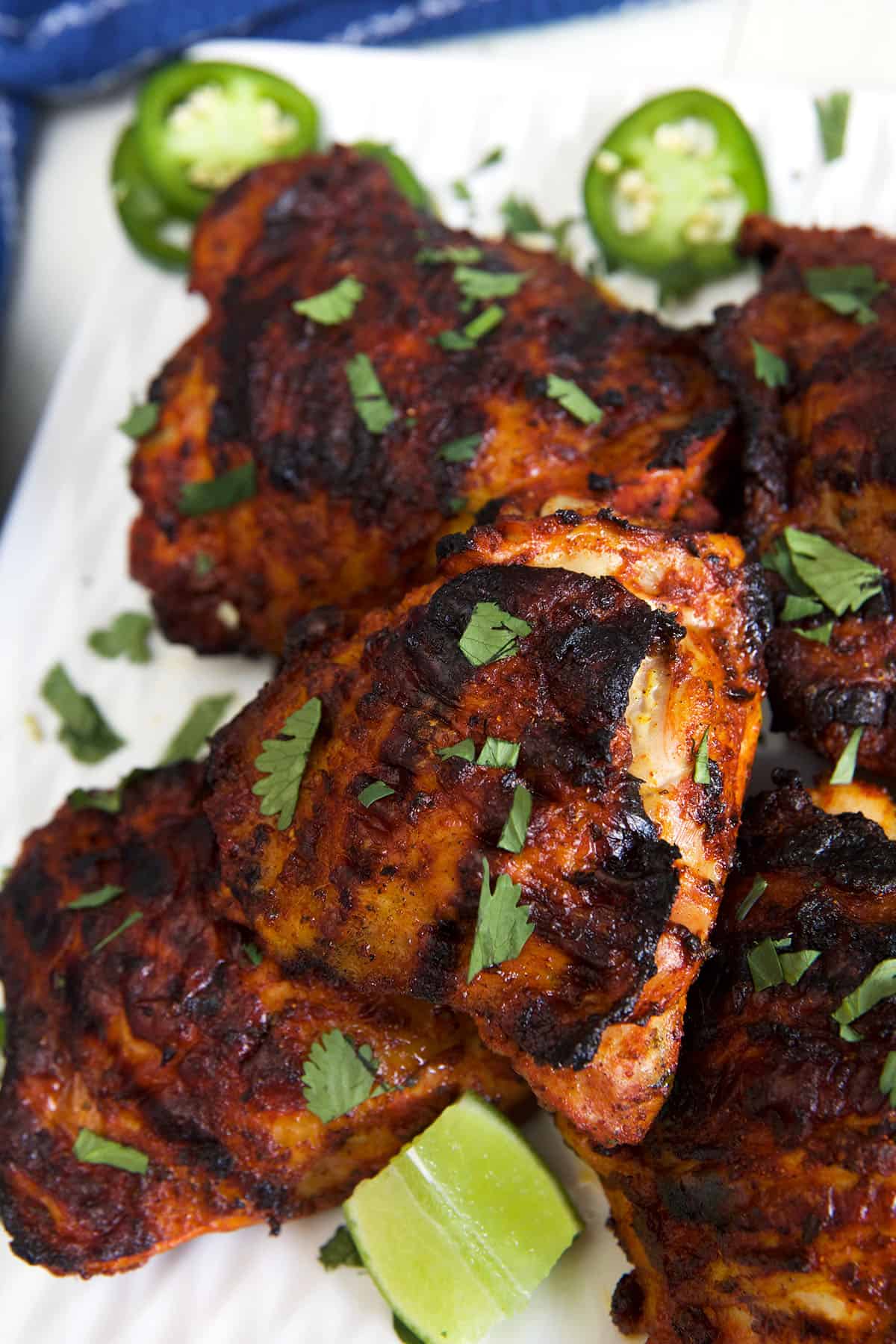Cilantro, limes, and jalapenos are placed on and around cooked pollo asado.