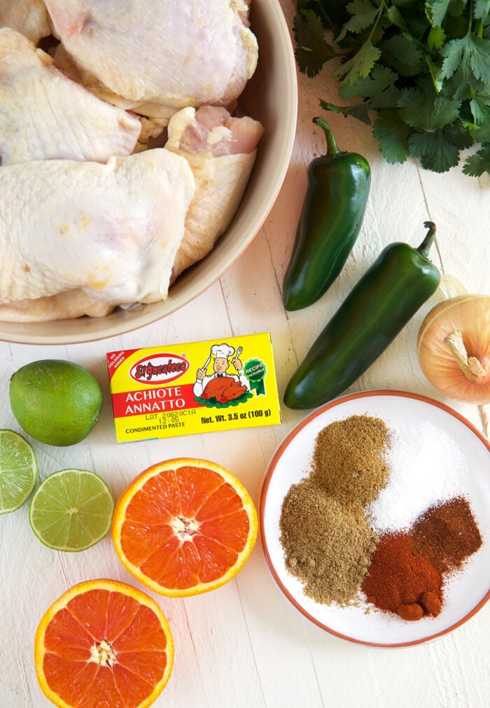 The ingredients for pollo asado are spread out on a white surface.