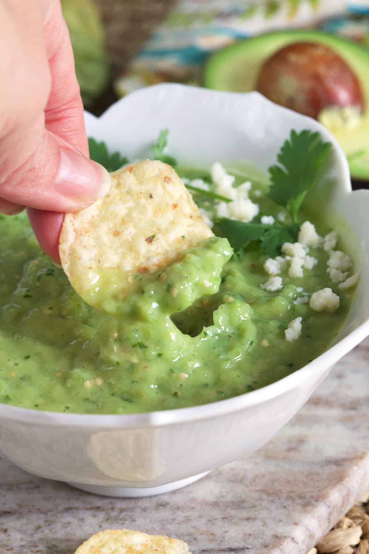 A tortilla chip is scooping up a bite sized portion of salsa.